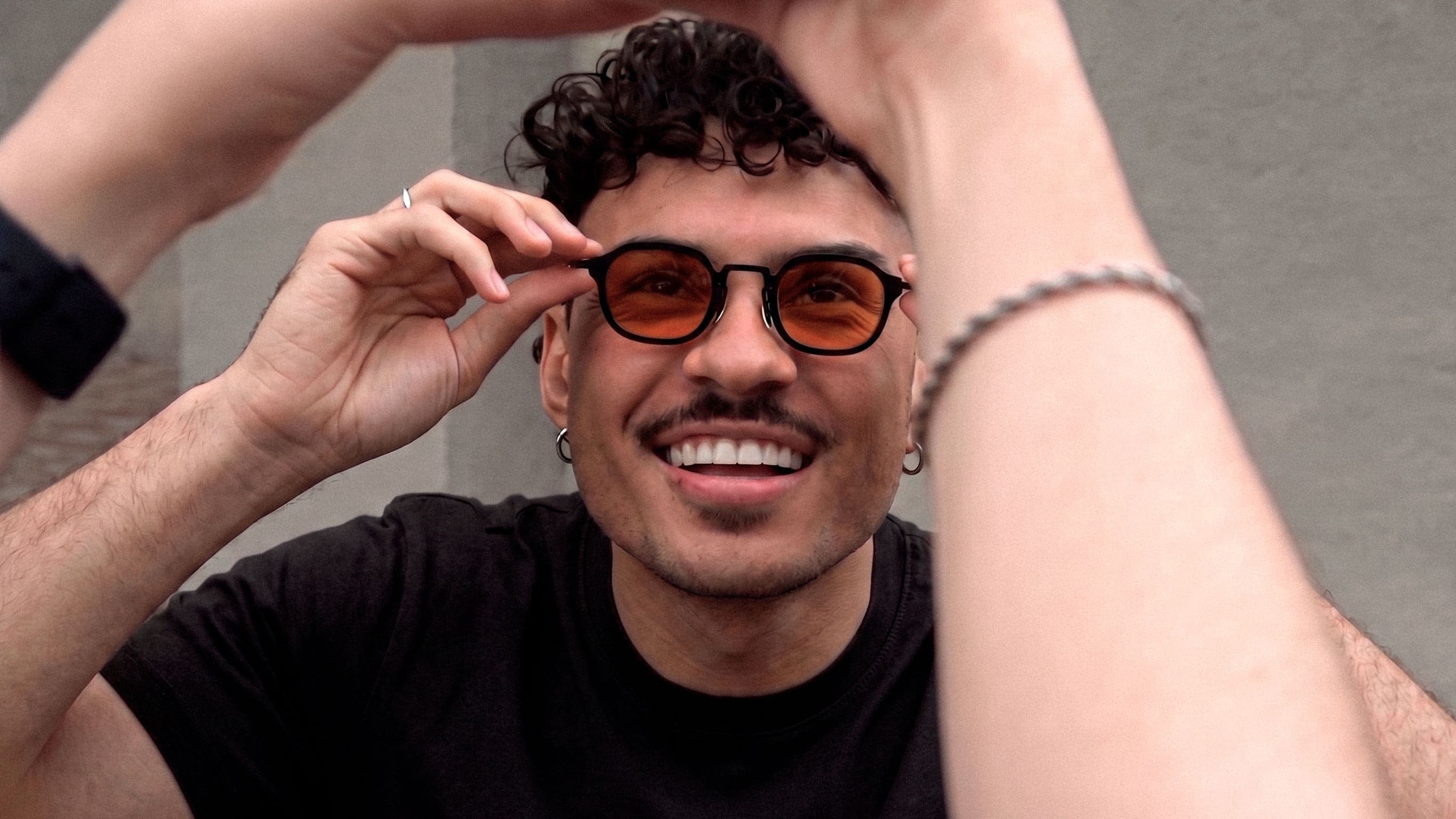 Man adjusting OØAK sunglasses with orange lenses